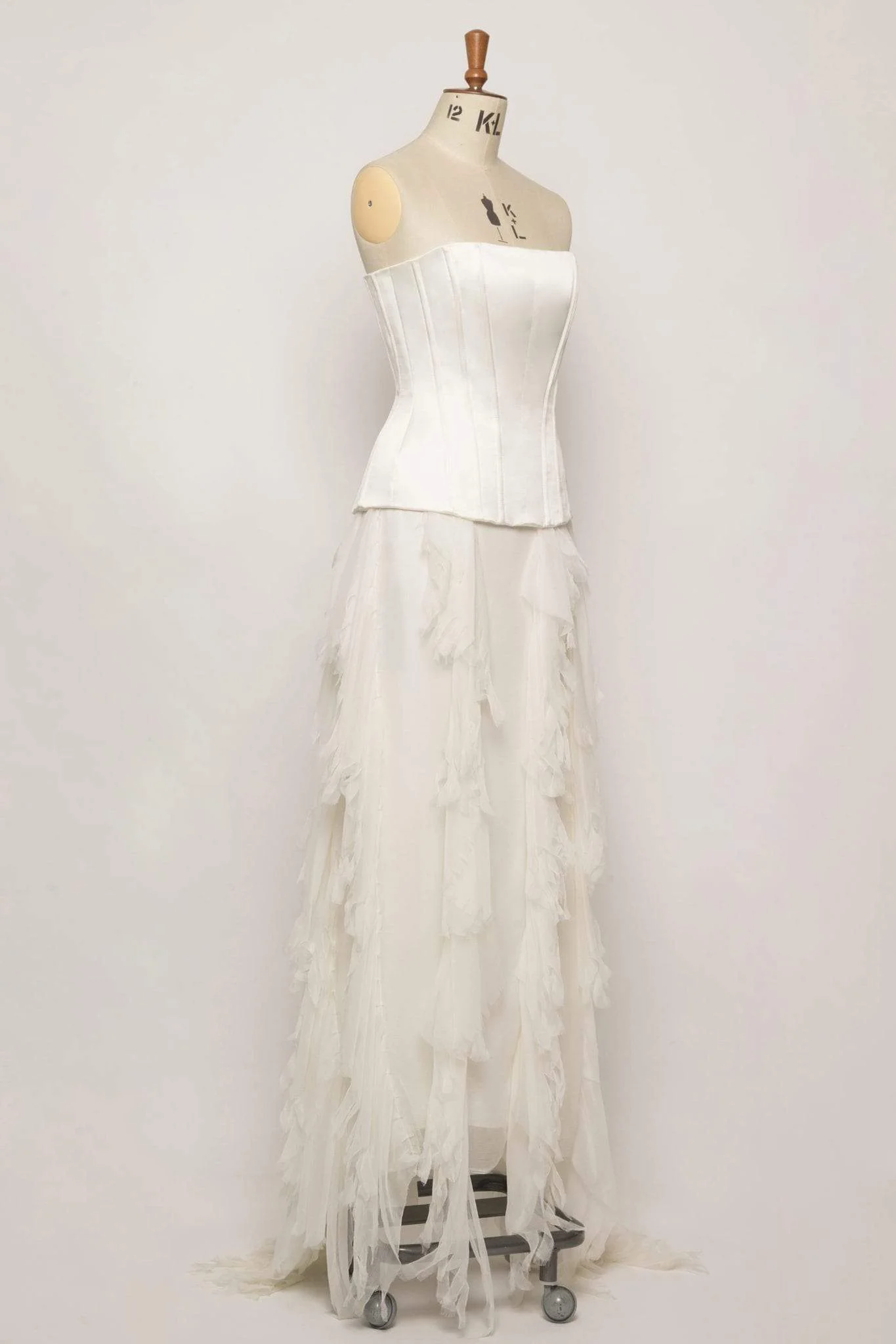 Unique two-piece strapless gown with heavily boned corset in duchess satin, soft fringed silk chiffon skirt, low drop waist, and covered working buttons.