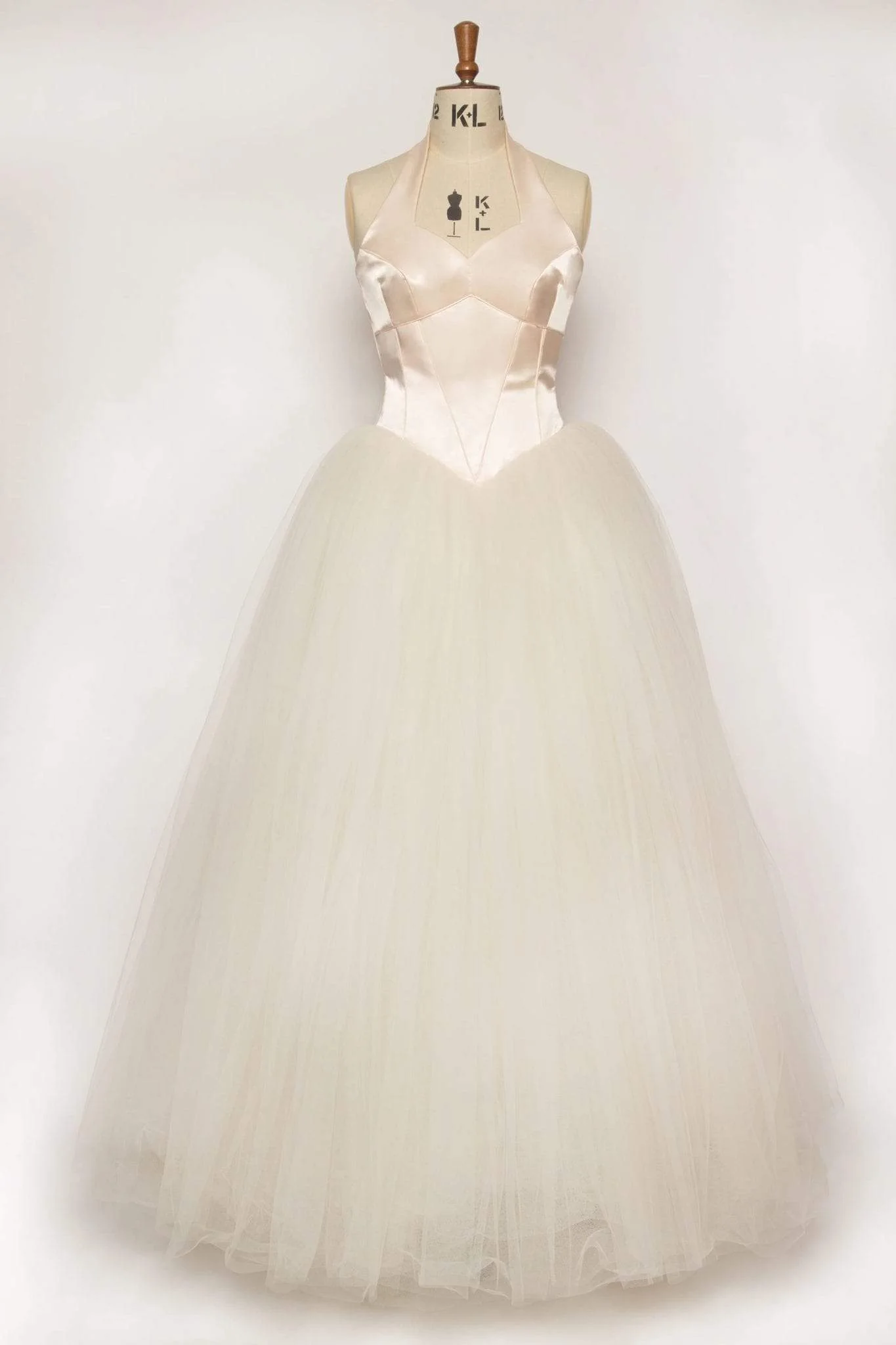 Peach duchess satin halter gown with sweetheart bodice, full tulle skirt, piped edges, and covered buttons, perfect for a fairytale princess look.