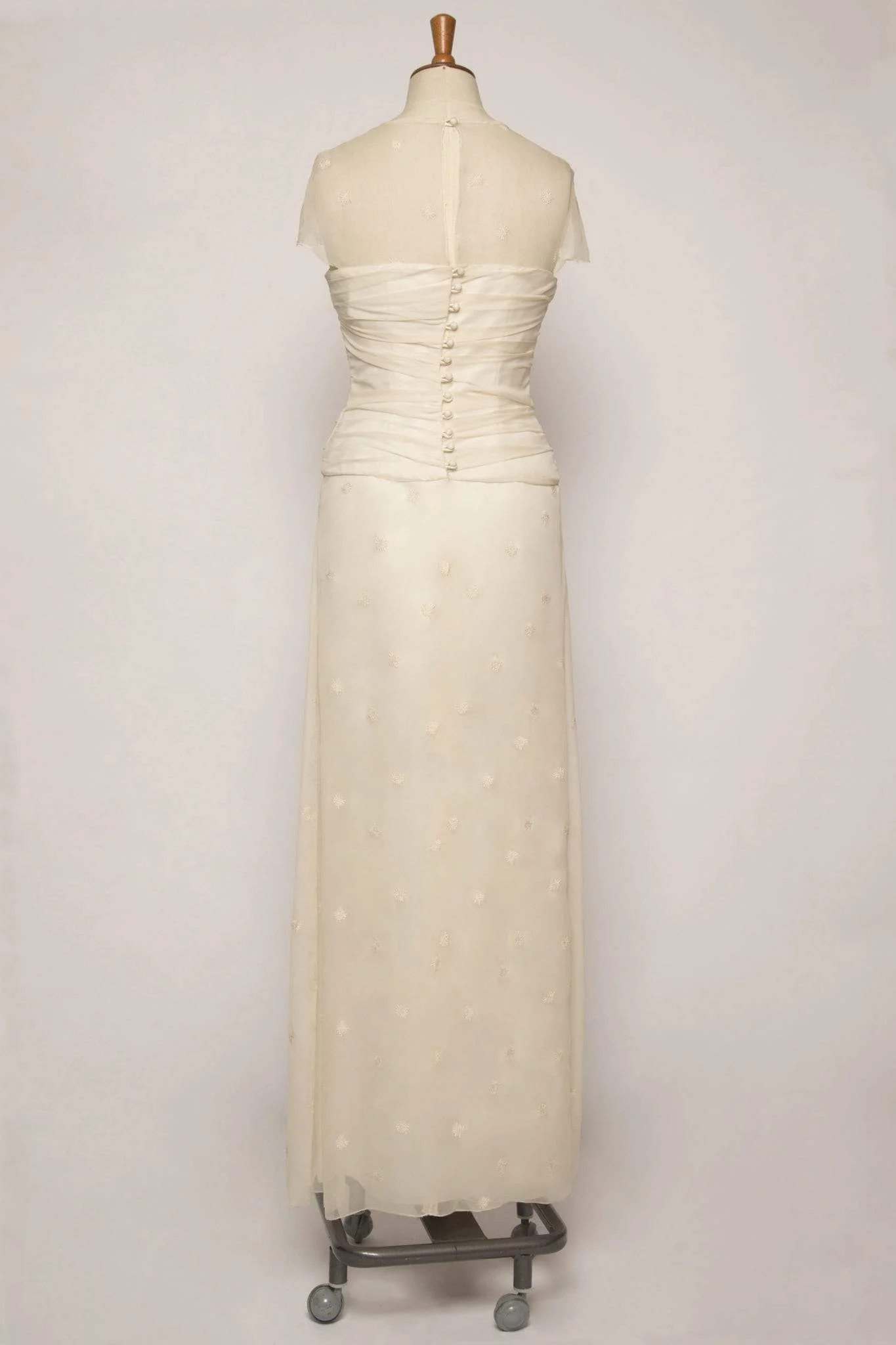Back view of long flowing ruched ivory silk chiffon A-line dress, showing covered button and loop fastening