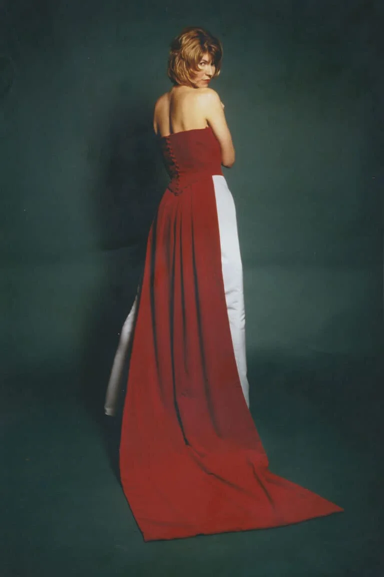 Three-piece bridal gown with a strapless ruby red velvet V-shaped basque bodice, duchess satin A-line skirt, detachable watteau train, and covered buttons. Back view