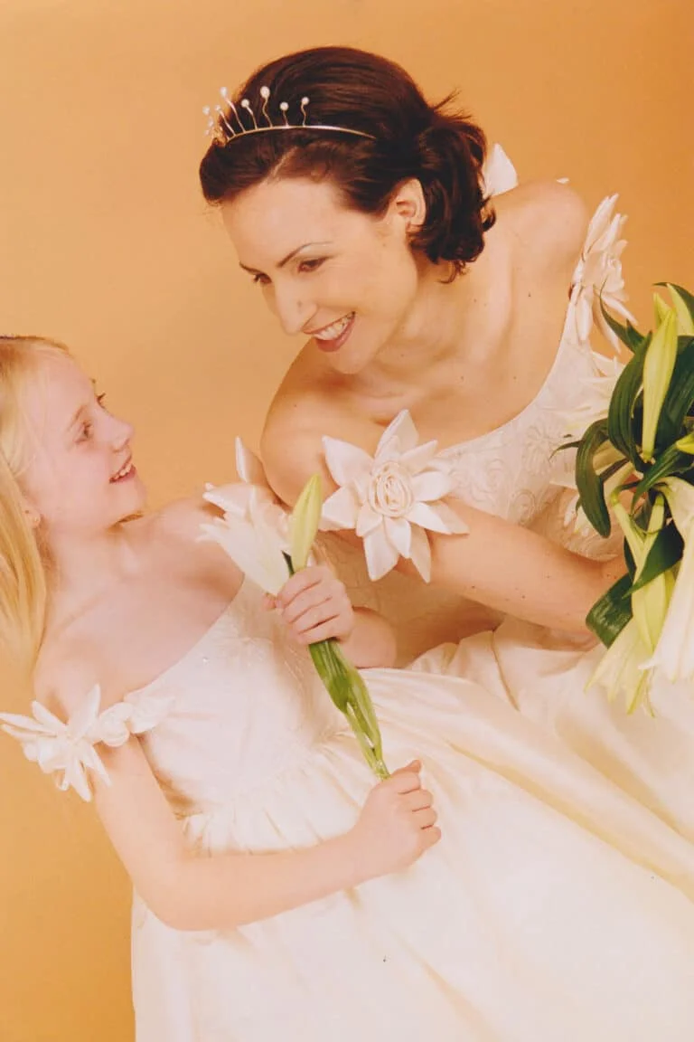 A pure silk off-the-shoulder ball gown with handmade satin flowers, alongside the matching bridesmaids dress